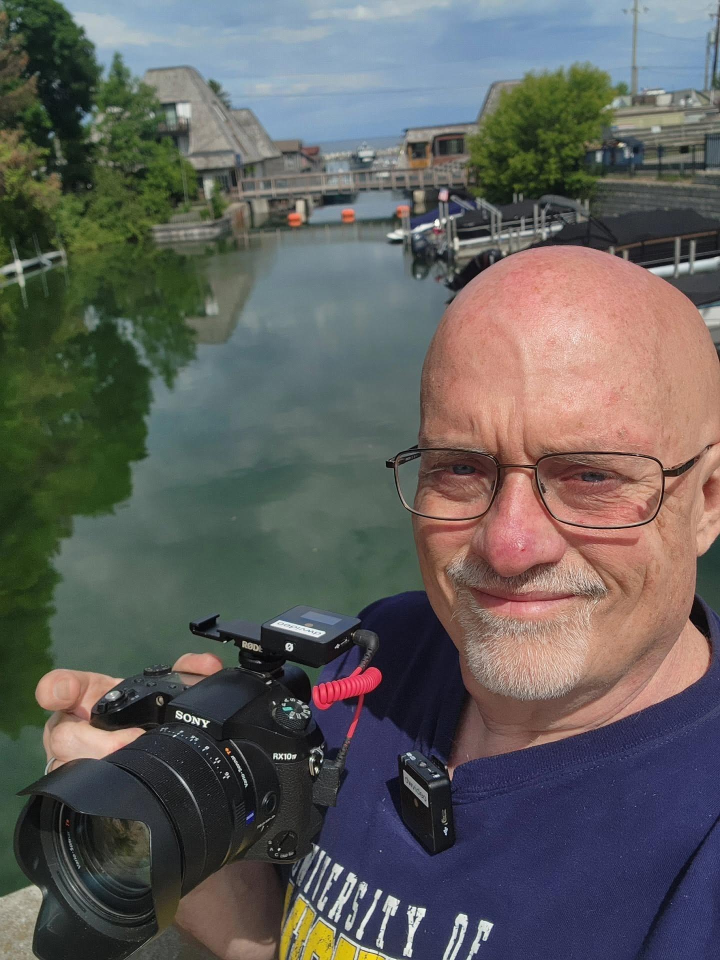 Duane Weed with his camera beside the waterfront in Fishtown, Leland, Michigan